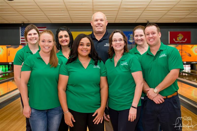 8 magnolia state bank employees take photo at bowling alley.