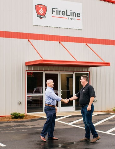 two men shaking hands in front fire line inc.